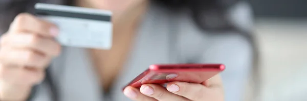 Mulher segurando cartão bancário e telefone em suas mãos close-up — Fotografia de Stock