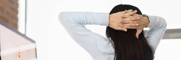 Mujer poniendo sus manos detrás de la cabeza en la mesa en la oficina — Foto de Stock