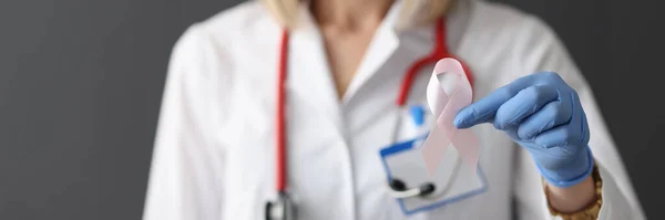 Doctor holding pink ribbon in his hand in rubber glove closeup — Stock Photo, Image