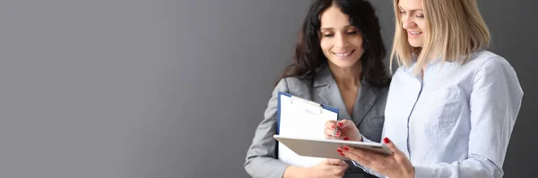 Zakenvrouw toont informatie aan collega op tablet en glimlacht — Stockfoto