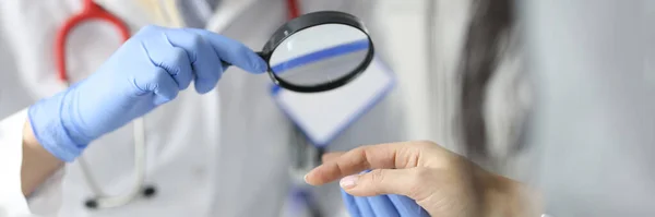 Dermatólogo médico mirando a los pacientes piel en las manos usando lupa en primer plano clínica —  Fotos de Stock