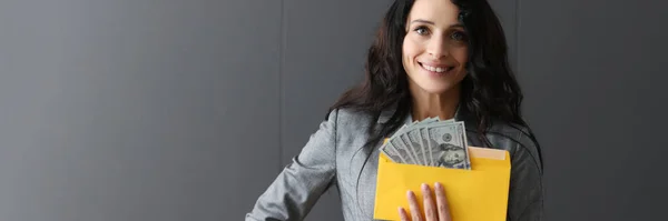 Mujer sonriente sosteniendo un sobre con dólares americanos. —  Fotos de Stock