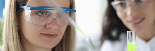 Cientistas femininas derramando líquido químico da pipeta em tubo de ensaio em laboratório — Fotografia de Stock