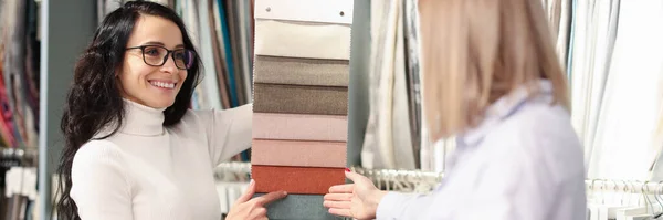 Woman choosing color of fabric from many samples in store — Stock Photo, Image