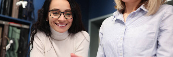 Two women looking into digital tablet and smiling in workshop
