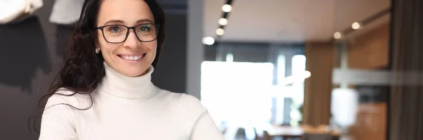 Mujer morena con gafas sonriendo y sosteniendo bolígrafo sobre portátil — Foto de Stock