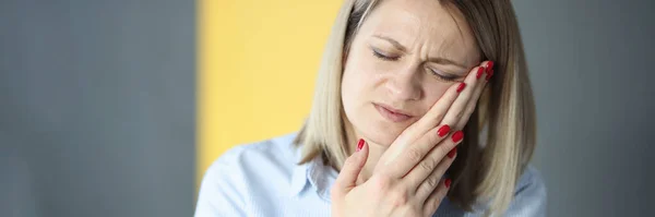 Young woman closing eyes and holding cheek with hand — Stock Photo, Image