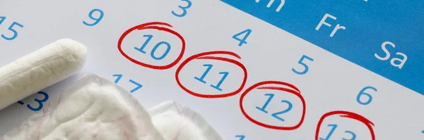 Las toallas sanitarias y los tampones están en el calendario. Los números están rodeados en pluma roja —  Fotos de Stock