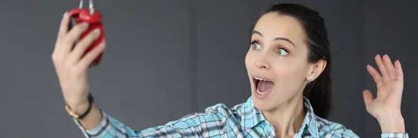 Verrast vrouw met een rode wekker in haar handen — Stockfoto