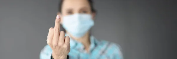 Mujer con máscara médica protectora mostrando el dedo medio de la mano de cerca —  Fotos de Stock