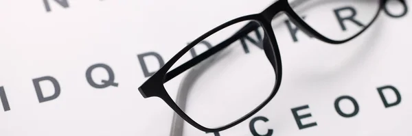 Test çizelgesinde uzanan siyah çerçevelerde görme gözlüğü — Stok fotoğraf