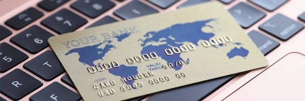 Credit bank card lying on laptop keyboard closeup