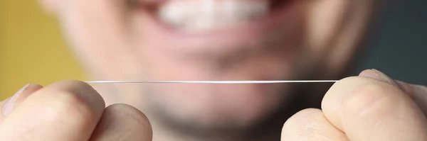 Homme souriant tenant de la soie dentaire dans ses mains — Photo