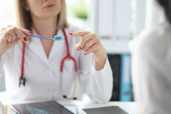 El médico muestra el cepillo de dientes al primer plano del paciente —  Fotos de Stock