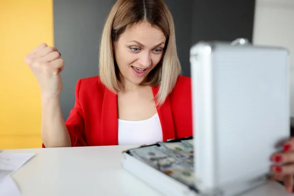 Joyful woman looks into suitcase with money — Stock Photo, Image