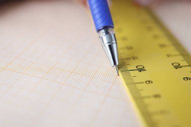 Masada cetvel boyunca çizim çizgisi olan grafik kağıdı var.