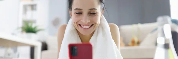 Femme en vêtements de sport couché sur tapis de gymnastique et regardant sur l'écran du téléphone — Photo