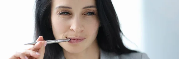 Porträt einer jungen brünetten Frau mit Kugelschreiber im Mund — Stockfoto