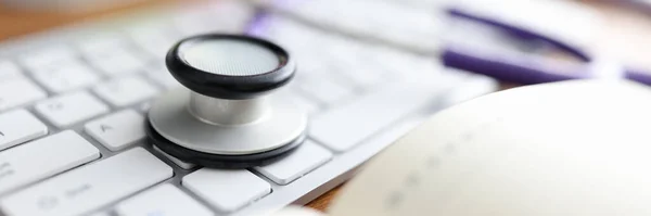 Stethoskop liegt auf Computertastatur in Arztpraxis in Großaufnahme — Stockfoto