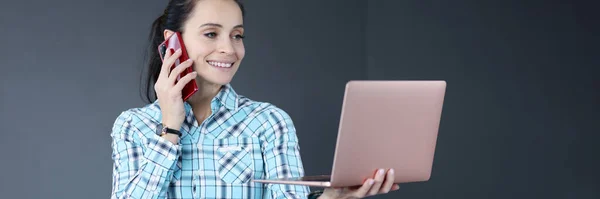 Junge Frau hält Laptop in der Hand und telefoniert — Stockfoto