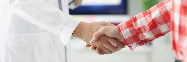 Médecin tenant des documents et serrant la main des patients à la clinique — Photo