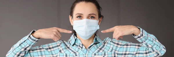 얼굴에 있는 의료용 보호 마스크에 손가락을 대고 있는 여자 — 스톡 사진