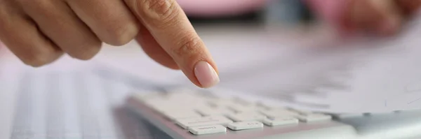 Žena prst nad klávesnicí počítače obsahuje dokumenty s finančními indikátory — Stock fotografie