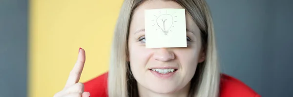 Affärskvinna har klistermärke med målad glödlampa i ansiktet — Stockfoto