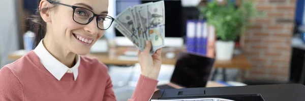 Usmívající se žena drží bankovky v rukou a tiskne je na tiskárnu — Stock fotografie
