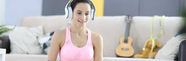 Woman in headphones and tracksuit making notes on notebook on online weight loss trainings concept — Stock Photo, Image