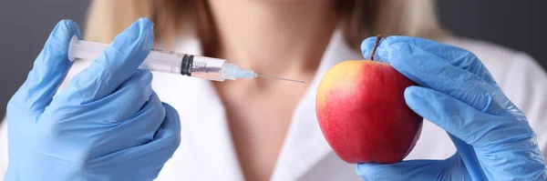 Doutor está segurando seringa com agulha e uma maçã — Fotografia de Stock