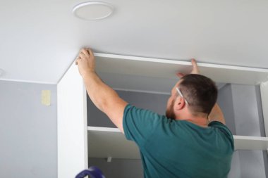 Yeni beyaz dolapla çalışan konsantre erkek işçilere yakın plan.