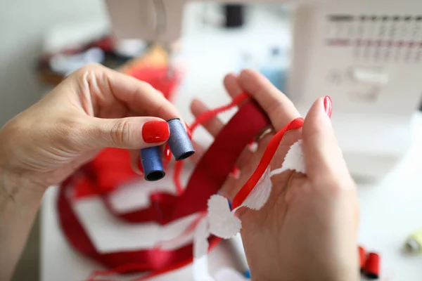 Close-up van het vrouwelijke bedrijf haspel van rode draad en decor voor jurk — Stockfoto