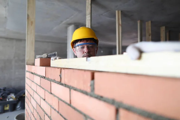 Retrato do construtor que coloca tijolos usando ferramentas especiais. Trabalhador construção de paredes de tijolo — Fotografia de Stock