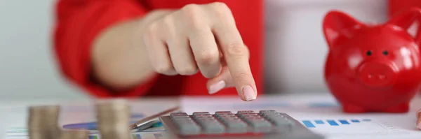 Woman counting cash coins on calculator closeup