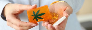 Kadın eli, bir kavanoz marihuana hapı tutuyor.