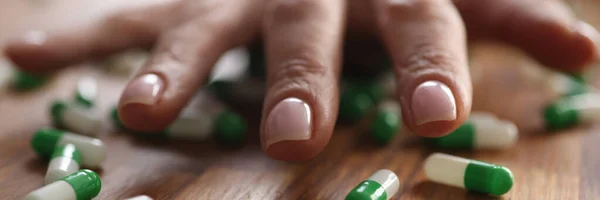 Vrouwelijke hand liggend op verspreide capsules closeup — Stockfoto