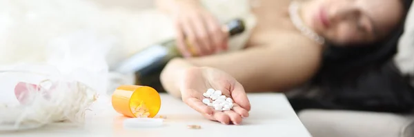 Bride in wedding dress lies on couch with pills in her hand — Stock Photo, Image