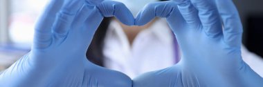Hand of doctor in protective medical gloves is covering heart closeup clipart