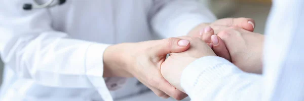 Doctor holding hands of patient in clinic closeup — Stock Photo, Image