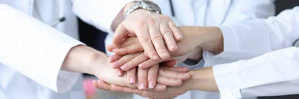 Group of doctors putting their hands together in clinic closeup — Stock Photo, Image