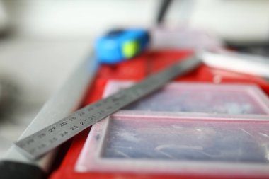 Metal cetvelin yakın plan görüntüsü kırmızı kutunun üzerinde enstrümanlarla duruyor