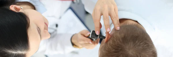 Otorhinolaryngologist examining patient with otoscope top view closeup — Stock Photo, Image