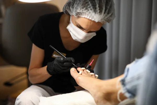 Pedicure mistrz w maskach i rękawiczkach farby paznokcie — Zdjęcie stockowe