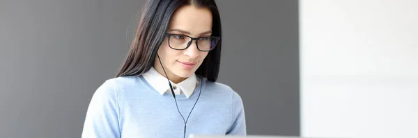 Mladá žena ve sluchátkách při pohledu na monitor notebooku — Stock fotografie