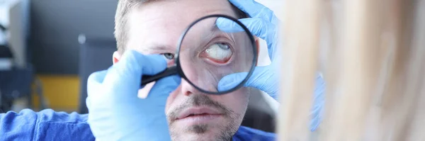 Dokter memeriksa mata pasien dengan kaca pembesar menutup — Stok Foto