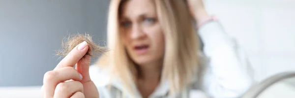 Gefrustreerde vrouw houdt knot van haar haar in haar hand — Stockfoto