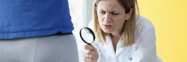 Doctor examines male organs through magnifying glass