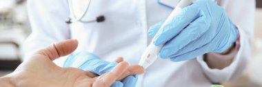 Eldivenli doktor hastaların parmaklarını neşterle deliyor.