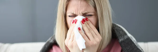 Sick woman wiping her nose with paper napkin